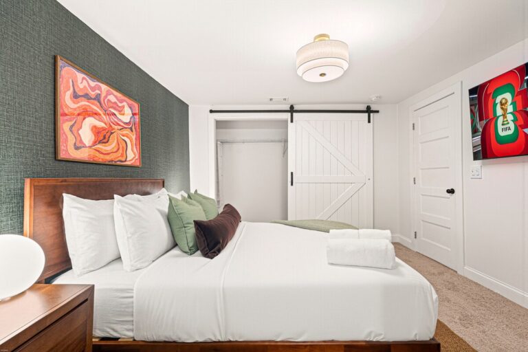 Bedroom 3 at Luxury 5BR Oasis in Atlanta, GA - queen bed with plush bedding, a 55-inch mounted smart TV and a sliding barn door